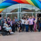 Students, faculty, and staff celebrate under a rainbow arch 